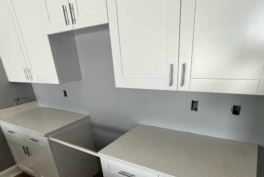 A modern kitchen featuring white cabinets and countertops, creating a bright and clean aesthetic.