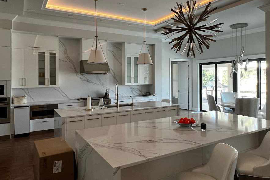 A modern kitchen featuring elegant marble countertops and a spacious central island for cooking and dining.