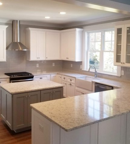 A modern kitchen featuring white cabinets and a spacious center island for cooking and dining.