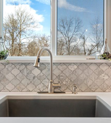 A kitchen sink with a window positioned in the center, allowing natural light to illuminate the space.