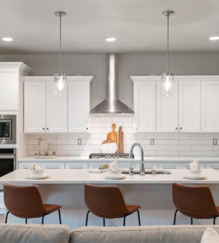 A modern kitchen featuring white cabinets and a spacious center island for cooking and dining.
