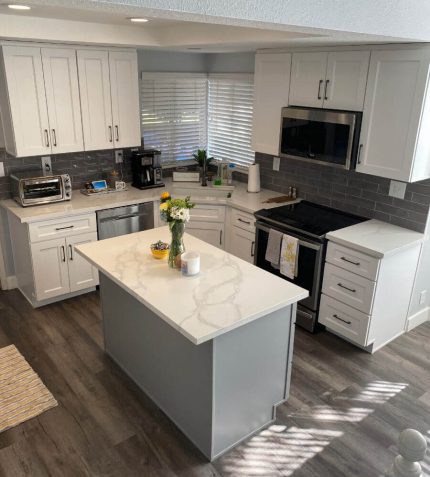 A modern kitchen featuring white cabinets and a sleek marble countertop.