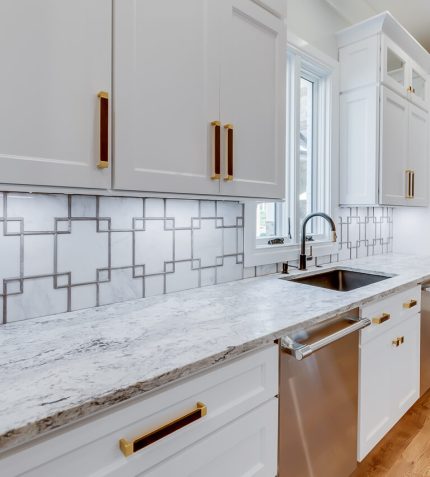 A modern kitchen featuring white cabinets complemented by elegant gold hardware.