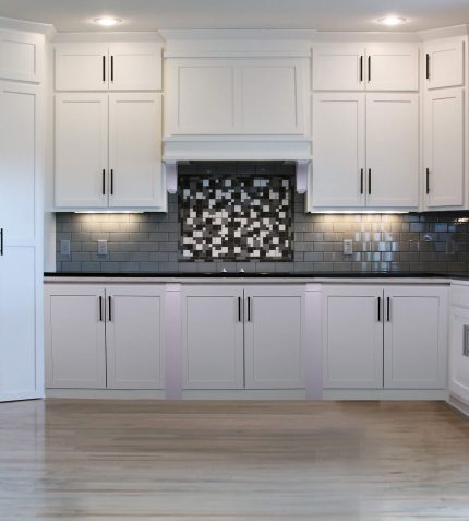 A modern kitchen featuring white cabinets and a stylish black and white tiled floor.