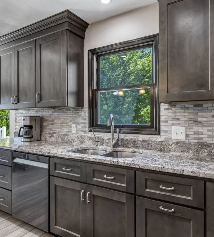 A modern kitchen featuring granite countertops and dark wood cabinets, showcasing a sleek and elegant design.