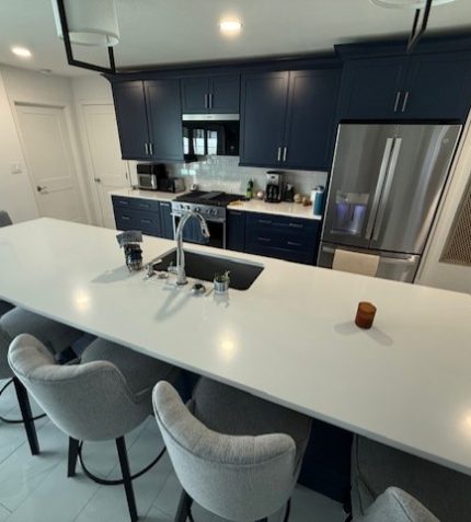 A kitchen featuring blue cabinets and white countertops, creating a modern and stylish atmosphere.