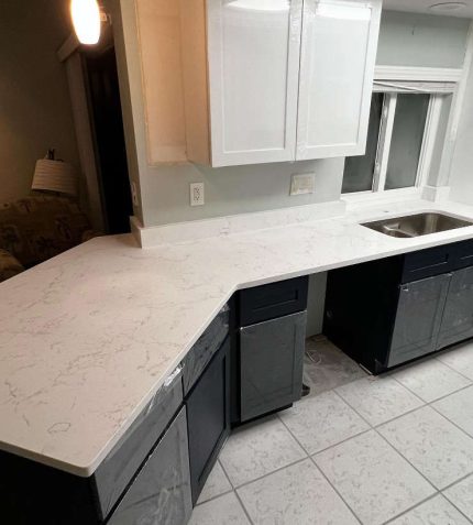 A modern kitchen featuring white cabinets and countertops, creating a bright and clean aesthetic.