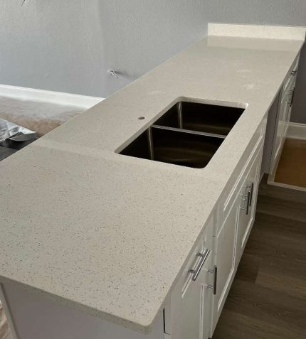 A kitchen counter featuring a sink, with utensils and a dish rack nearby, creating a functional cooking space.
