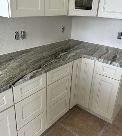 ranite countertops in a modern kitchen featuring sleek white cabinets.