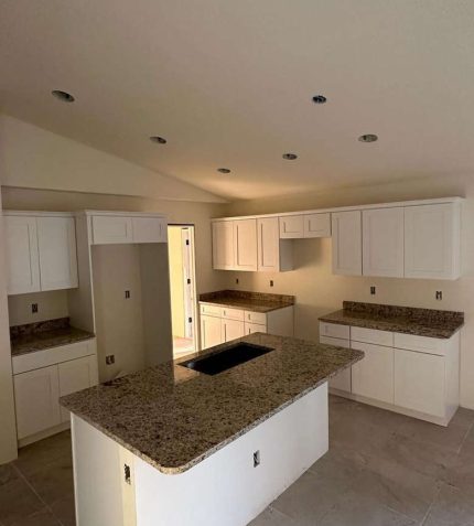 A modern kitchen featuring white cabinets and elegant granite countertops.