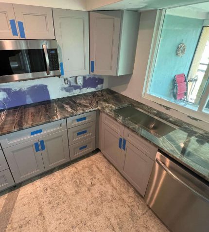 A modern kitchen featuring stainless steel appliances and stylish blue cabinets.