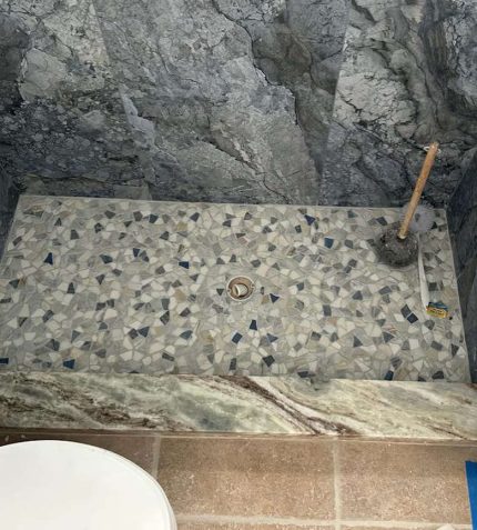 A bathroom featuring a shower and a toilet, with neutral-colored tiles and modern fixtures.