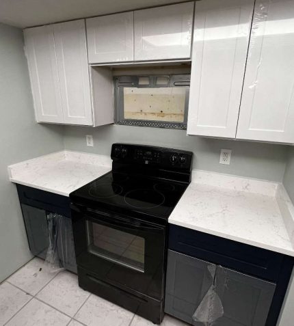A modern kitchen featuring white cabinets and a sleek black stove top.