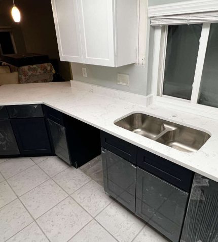 A modern kitchen featuring white countertops and sleek black cabinets, creating a stylish contrast.