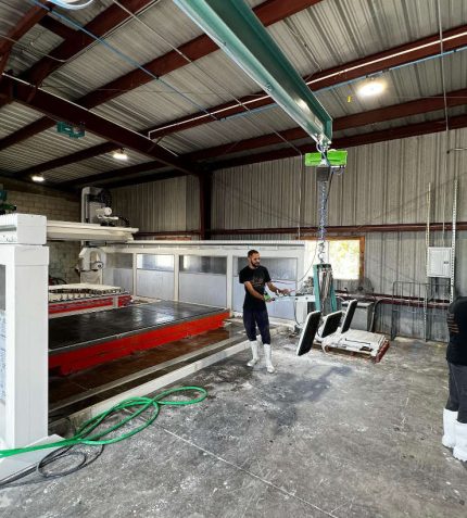 A man operates a machine inside a warehouse, focused on his task amidst industrial equipment and storage.