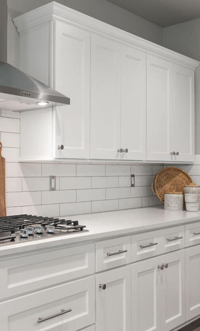 A modern kitchen featuring white cabinets and a sleek stove top, creating a bright and inviting cooking space.