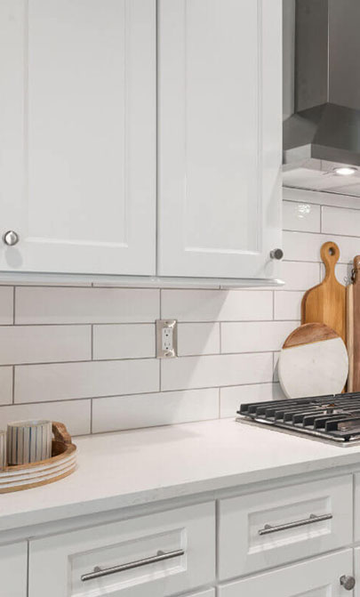 A modern kitchen featuring white cabinets and a sleek stove top, creating a bright and inviting cooking space.